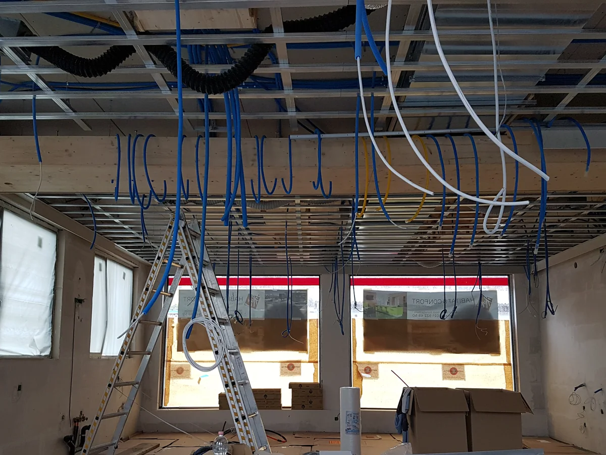 Chantier intérieur avec ossature de plafond et réseaux en cours de pose