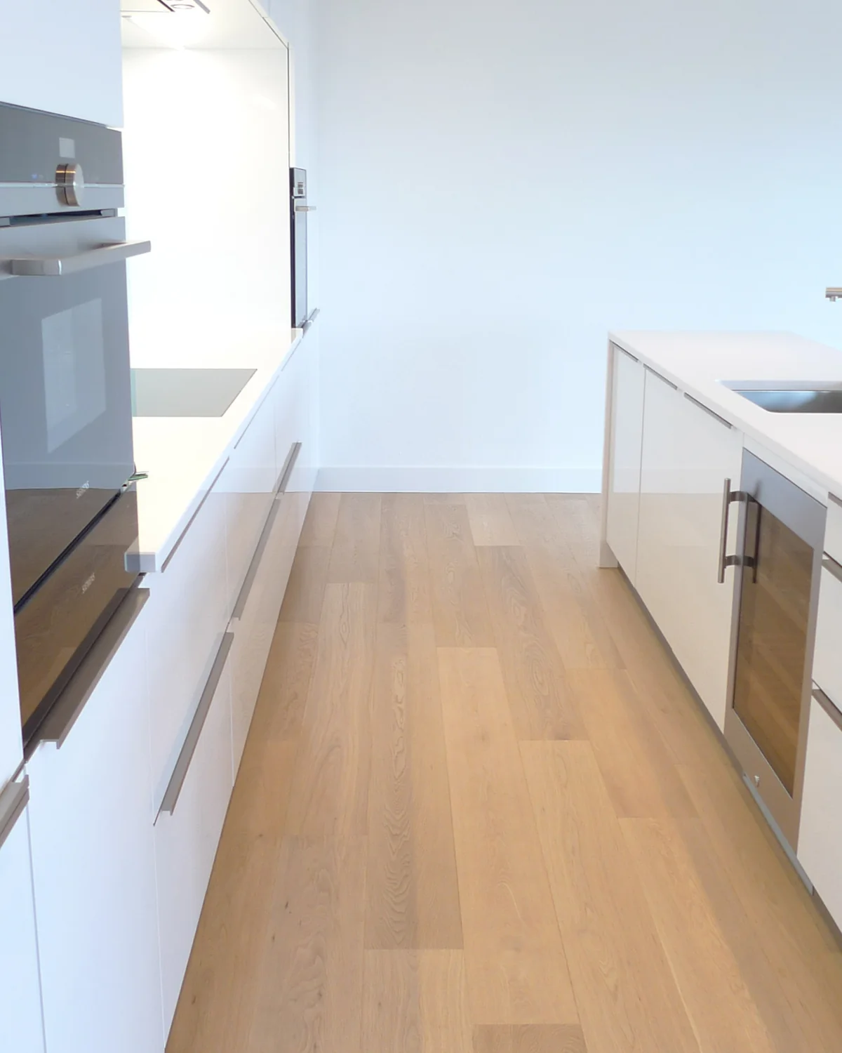 Cuisine blanche avec un sol en parquet clair