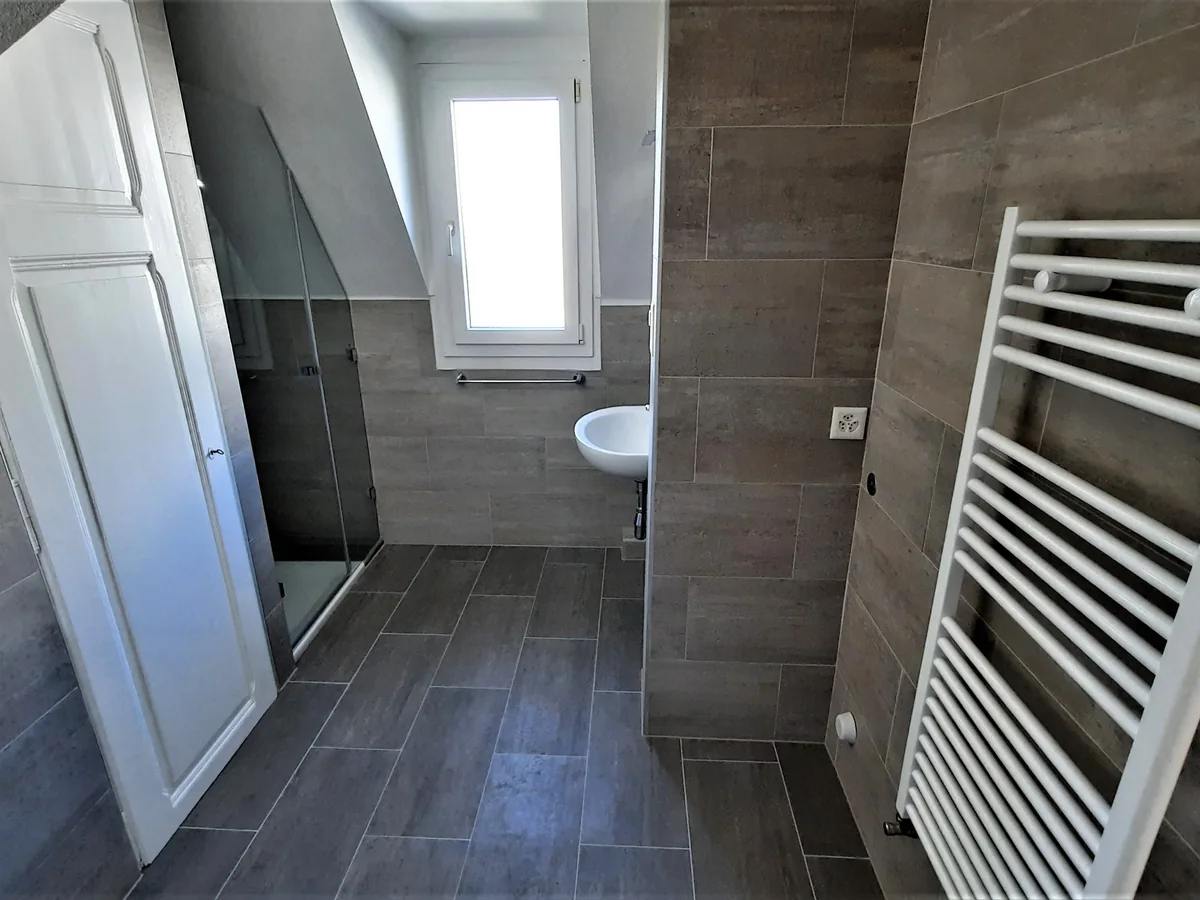 Salle de bain avec douche, carrelage gris et sèche-serviettes