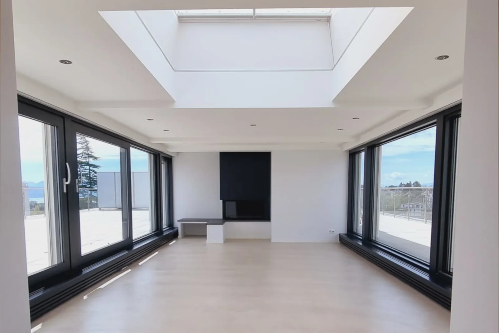 Même séjour après rénovation, avec plafond fini et baies vitrées sombres